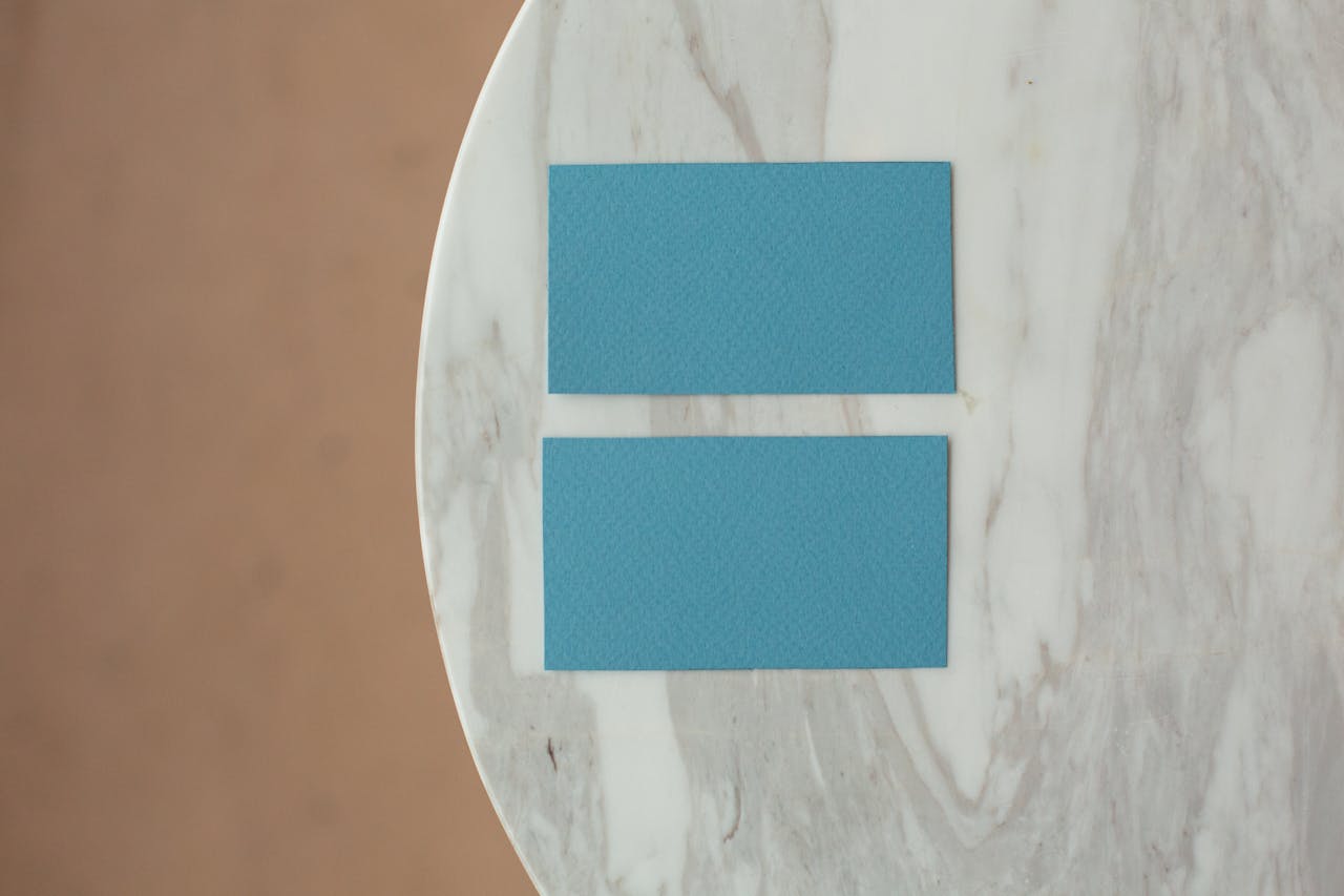 Top view of blue mock up business cards with copy space placed on marble round table in light room of studio